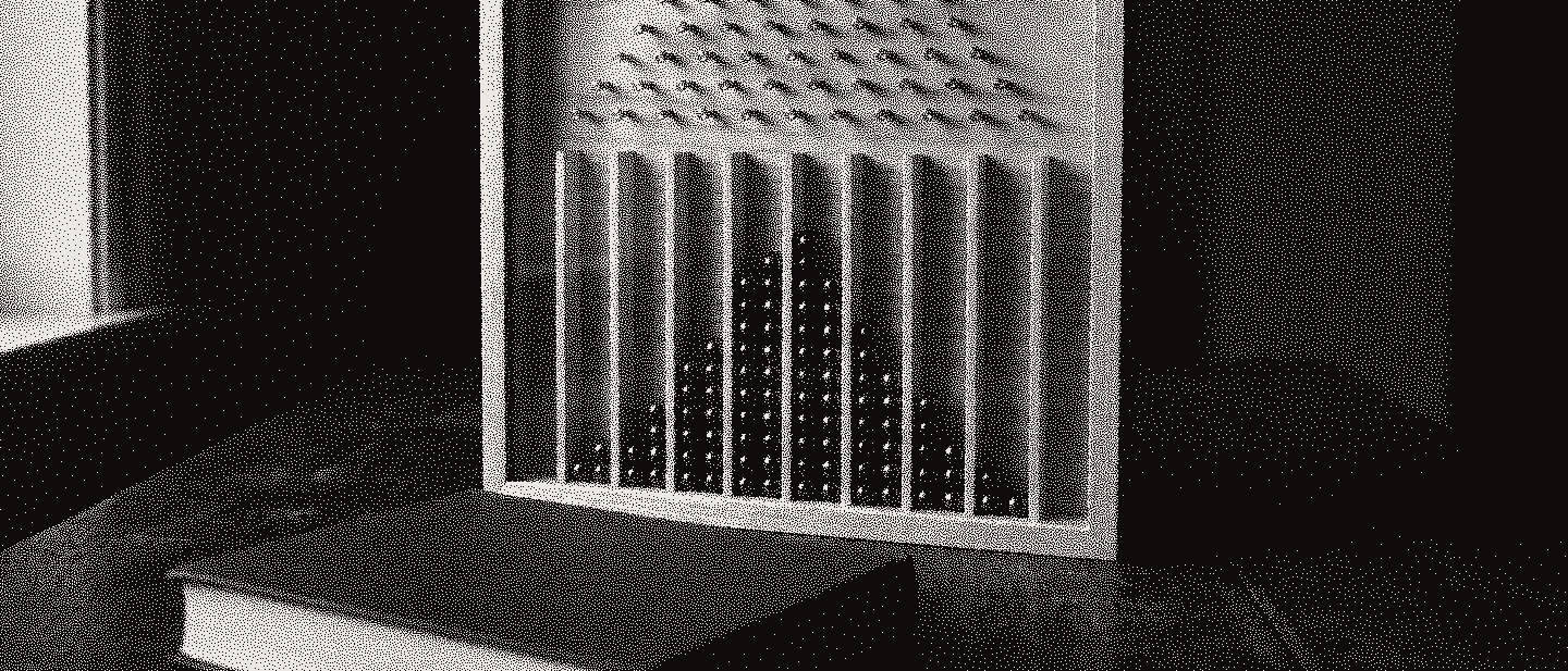 A wooden pin board with a glass front, steel balls stacked in a bell curve in its bins, and a closed green cloth book before it.