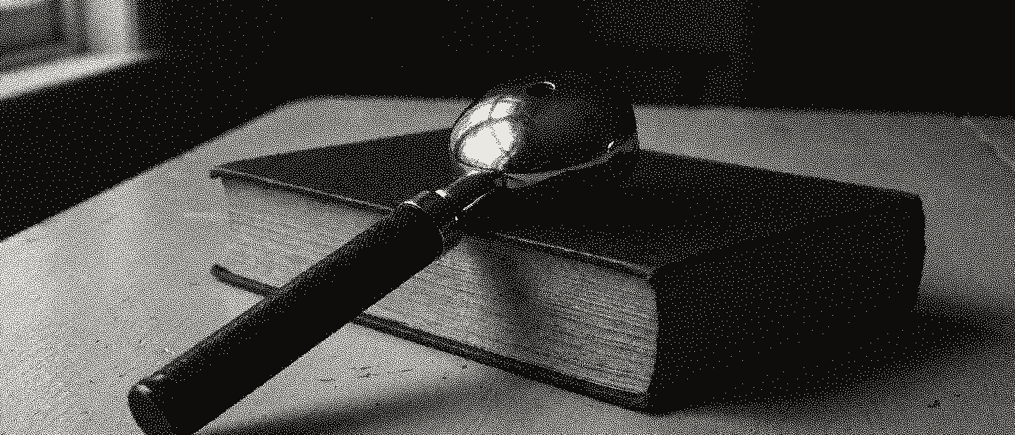 An old ophthalmoscope with a black knurled handle and a chrome head, resting on a closed red cloth book on a pale painted table.