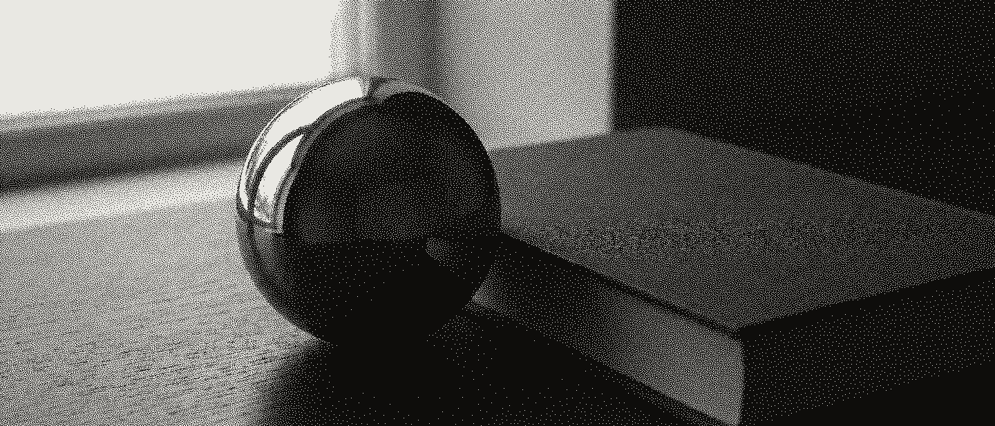 A polished steel sphere reflecting a window, resting against a closed graphite-grey cloth book on a dark table.