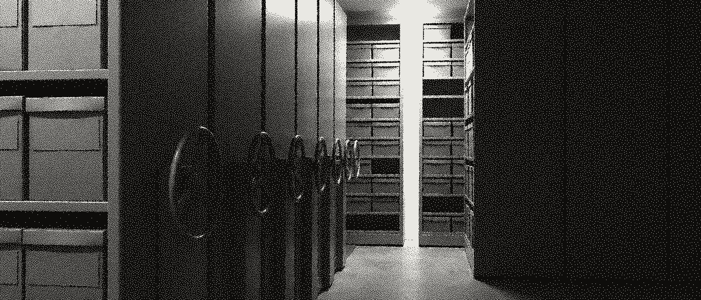 Rows of rolling archive shelving pushed together, one aisle opened and lit, handwheels on the stack ends.